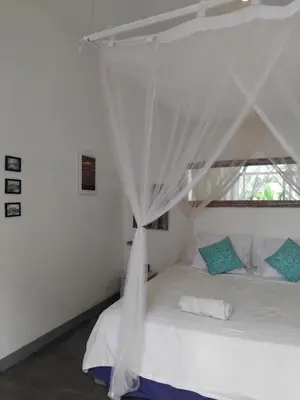 a bedroom with a white bed with a canopy at Jimbaran room 01 in Jimbaran
