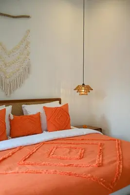a bed with orange and white pillows and a lamp at Villa Bella Wilson III in Seminyak