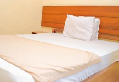 a bedroom with two beds with white sheets and a wooden headboard at Hotel Damai in Denpasar