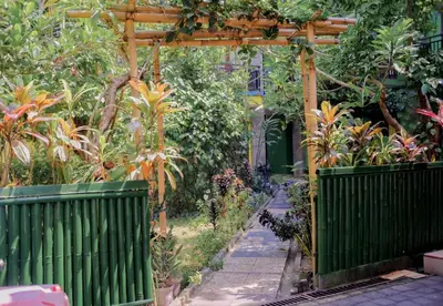 a garden with a green fence and plants at Hotel Damai in Denpasar
