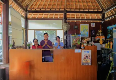 three people standing behind a counter in a restaurant at Hotel Damai in Denpasar