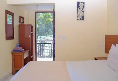 a bedroom with a bed and a door to a balcony at Hotel Damai in Denpasar