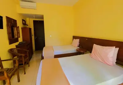 a hotel room with two beds and a table and chairs at Hotel Damai in Denpasar