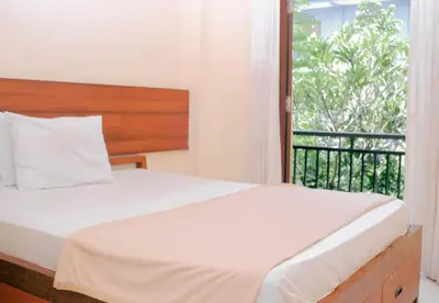 a bedroom with a bed and a balcony at Hotel Damai in Denpasar