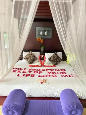 a bed with two purple chairs in a bedroom at Classic Villa with Private Pool in Kuta