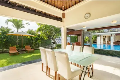 an outdoor dining room with a glass table and white chairs at 4 Bedroom Private Villa Umalas 2 in Seminyak