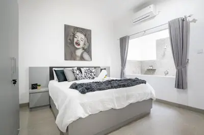 a white bedroom with a large bed and a window at Aster Villa by iBali Management in Legian