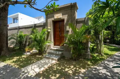 a small house with a wooden door in a yard at Aster Villa by iBali Management in Legian