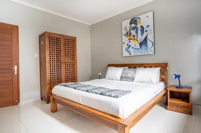 a bedroom with a bed and a painting on the wall at Melati Villa by iBali Management in Legian
