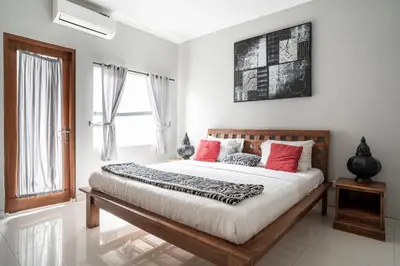 a bedroom with a large bed with red pillows at Melati Villa by iBali Management in Legian