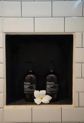 two bottles of soap and a flower on a shelf at Oemah Djoglo Kerobokan in Kerobokan