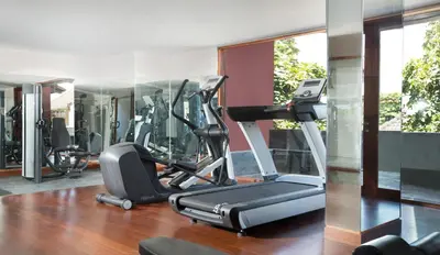 a gym with a treadmill and elliptical machines at Amnaya Resort Kuta in Kuta