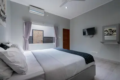 a white bedroom with a large bed and a window at 3 Bedroom Villa Mawar walk to Beach Legian in Legian