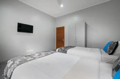 two beds in a room with a tv on the wall at 3 Bedroom Villa Mawar walk to Beach Legian in Legian
