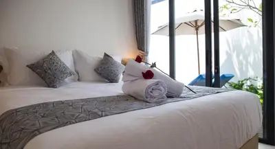 a white bed with a pillow with two roses on it at Villa Kumala Sari in Seminyak