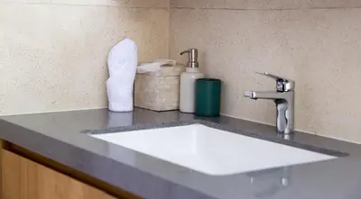 a bathroom counter with a white sink and a faucet at Villa Kumala Sari in Seminyak