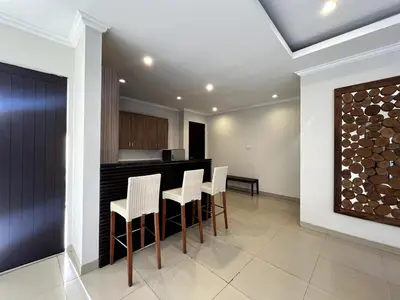 a kitchen with a bar with white chairs in it at White Lotus Villa by Miel Property in Seminyak