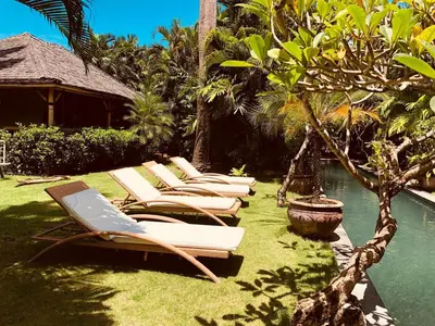 a row of lounge chairs sitting next to a pool at Large Private Villa, central Seminyak, Bali in Seminyak
