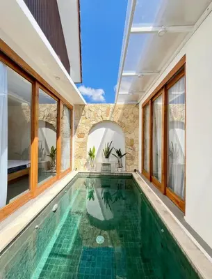 an indoor pool in a house with glass windows at Villa Boginville in Kerobokan