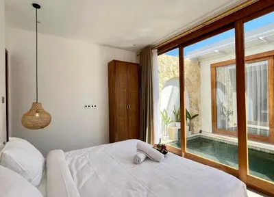 a bedroom with a bed and a swimming pool at Villa Boginville in Kerobokan