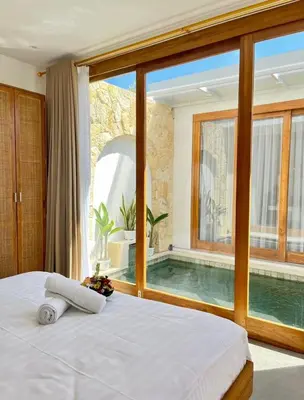 a bedroom with a large window and a swimming pool at Villa Boginville in Kerobokan