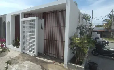 a white building with a gate and a motorcycle parked at Villa Boginville in Kerobokan
