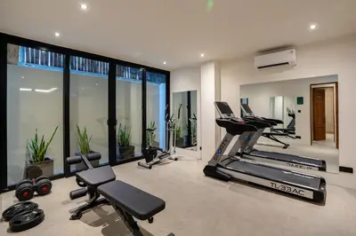 a gym with treadmills and exercise equipment and windows at Avanya Luxury Apartment by Pertama Management in Seminyak