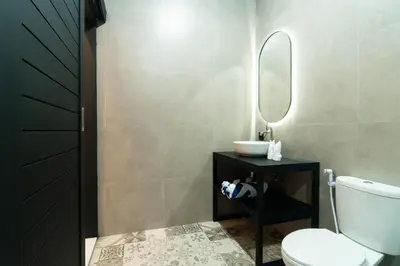 a bathroom with a toilet and a sink and a mirror at Stylish Umalas 2BR Villa With Private Pool in Kerobokan
