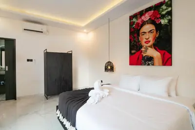 a white bedroom with a large painting on the wall at Stylish Umalas 2BR Villa With Private Pool in Kerobokan