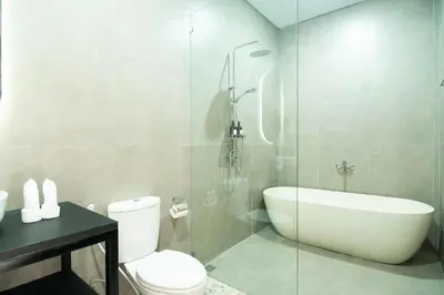 a bathroom with a toilet and a glass shower at Stylish Umalas 2BR Villa With Private Pool in Kerobokan