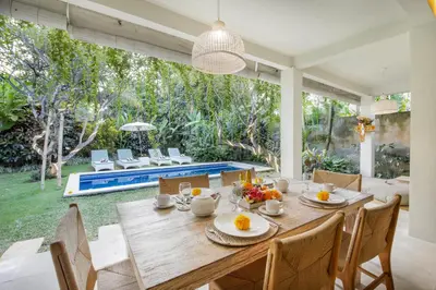 a dining room with a table and chairs and a pool at Villa Lodek Deluxe in Seminyak