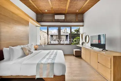 a bedroom with a large bed and a flat screen tv at Bamila Villa by Kozystay - Umalas in Canggu