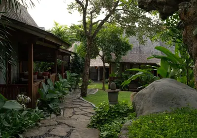 a garden with a stone walkway next to a building at Natajiwa Village close to Canggu and Seminyak in Seminyak