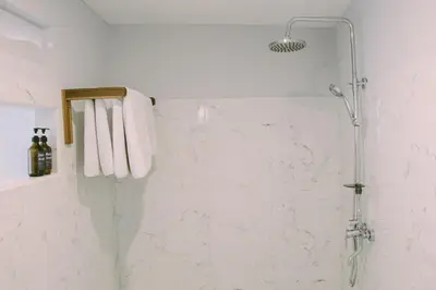 a bathroom with a shower with white marble walls at Sejati Villas - Petitenget in Seminyak