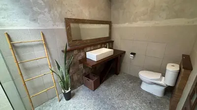 a bathroom with a toilet and a sink and a mirror at The Kutata in Jimbaran