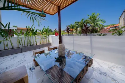 a table and chairs on a balcony with palm trees at Villa Kembar in Seminyak