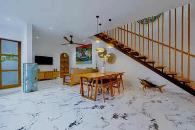 a living room with a table and a staircase at Villa Kembar in Seminyak