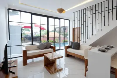 a living room with white furniture and large windows at Cozy Seminyak Loft 3 Bedroom Private Villa in Seminyak