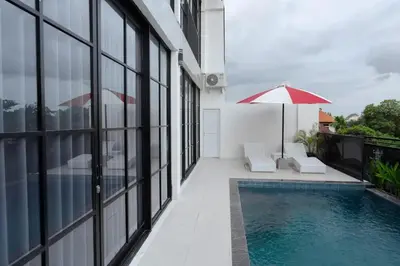 a balcony with a swimming pool and an umbrella at Cozy Seminyak Loft 3 Bedroom Private Villa in Seminyak