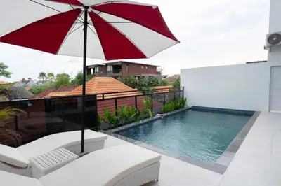 a red and white umbrella sitting next to a swimming pool at Cozy Seminyak Loft 3 Bedroom Private Villa in Seminyak
