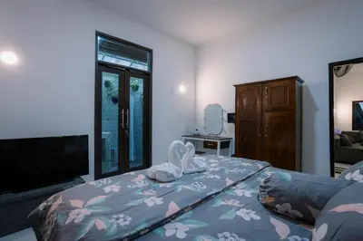 a bedroom with a bed with a television and a dresser at Hawaiian Beach House in Legian