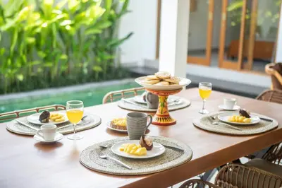 a table with plates of food and glasses of orange juice at Canggu - Villa Romy - 2 Bedrooms - Private Pool in Kerobokan