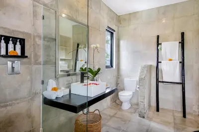 a bathroom with a toilet and a glass shower at Villa Roma in Seminyak