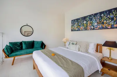 a bedroom with a bed and a green couch at Villa Roma in Seminyak