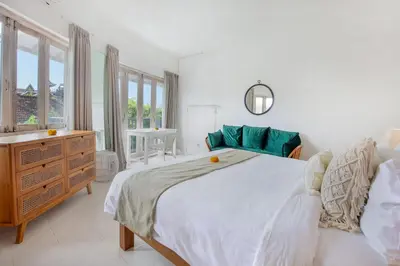a white bedroom with a large bed and a dresser at Villa Roma in Seminyak