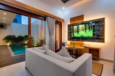 a living room with a white couch and a tv at Villa Boswellia Seminyak near Double Six Beach in Seminyak