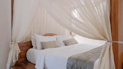 a bedroom with a white bed with a canopy at Jepun Villa by Betterplace in Seminyak