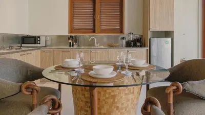 a kitchen with a glass table and some chairs at Jepun Villa by Betterplace in Seminyak