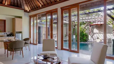 a living room with a table and chairs and a pool at Jepun Villa by Betterplace in Seminyak