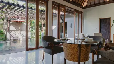 a dining room with a table and chairs and a pool at Jepun Villa by Betterplace in Seminyak